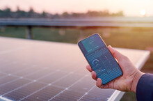 Man Hand Holding The Telephone For Monitoring Performance In Solar Power Plant(solar Cell). Alternative Energy To Conserve The World's Energy, Photovoltaic Module Idea For Clean Energy Production