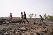 Group of young black African kids crossing a stony infertile field in the Sahel region; desertification concept