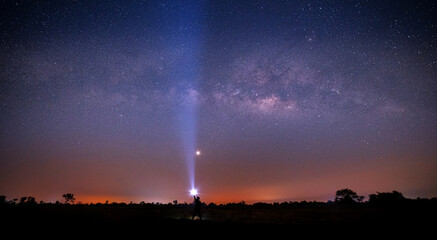 Wall Mural - silhouette tourist with flashlight in open field at night. space background with noise and grain. ni