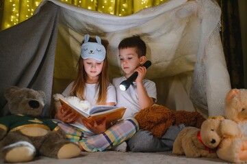 Little children reading bedtime story at home