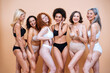 © oneinchpunch - Beauty image of a group of women with different age, skin and body posing in studio for a body positive photoshooting. Mixed female models in lingerie on colored backgrounds