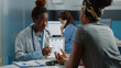 © DC Studio - African american doctor and patient looking at human skeleton on tablet. Black people analyzing osteopathy figure of bones anatomy on display for orthopedic diagnosis and healthcare.