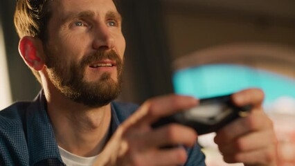 Wall Mural - Close Up Portrait of Young Man Spending Time at Home, Sitting on Couch in Stylish Loft Apartment and Playing Video Games on Console. Successful Male Using Controller to Concentrate Fully on the Game.