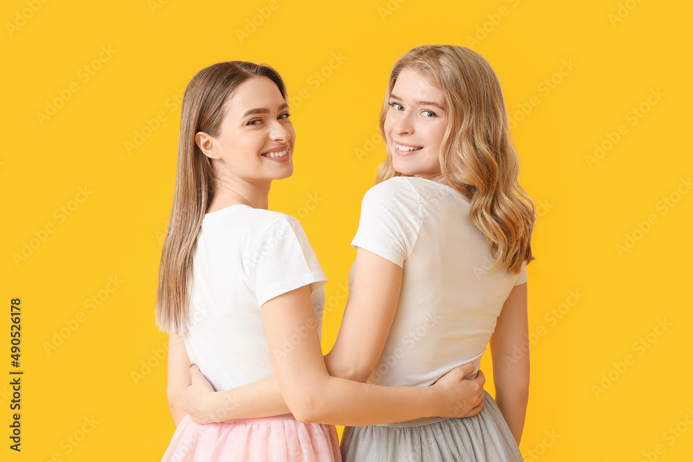 Portrait of young sisters on color background