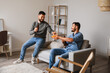 © Pixel-Shot - Male friends drinking beer on sofa at home