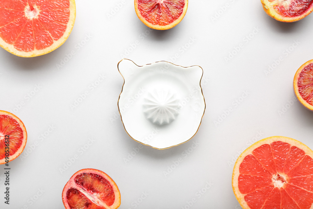 Ceramic juicer and grapefruits on light background