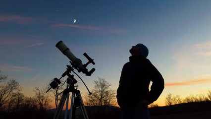 Wall Mural - silhouette of a man, telescope and countryside under evening skies.