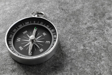 Close up of magnetic compass with black dial laying on stone surface and arrow pointing north, selective focus. Travel and tourism concept.