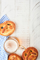 Wall Mural - Bavarian pretzels and glass of lager beer. Oktoberfest food menu, traditional salted pretzels over old white wooden background. Top view with space for text. Oktoberfest theme