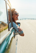 Feeling free on the open road. Cropped shot of an attractive woman hanging out of a car window while enjoying a roadtrip.