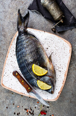 Poster - Fresh fish dorado. Dorado and ingredients for cooking at black slate table. Top view with copy space.