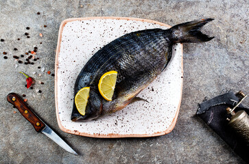 Wall Mural - Fresh fish dorado. Dorado and ingredients for cooking at black slate table. Top view with copy space.