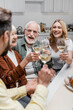© LIGHTFIELD STUDIOS - happy senior parents clinking wine glasses with adult son and daughter during easter celebration.