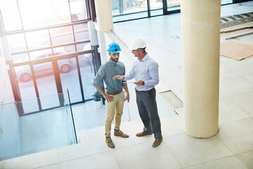 Poster - Inspecting the construction site. High angle shot of two businessmen talking in the lobby of their office.