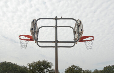 rusty old double basketball hoop in the park, outdoor recreation area.