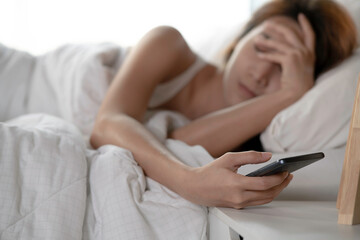 young sleeping woman wake up to turn off the alarm or check notification on a mobile phone and put t
