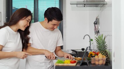 Wall Mural - couple cooking and preparing vegetables according to a recipe on a tablet computer in the kitchen at home