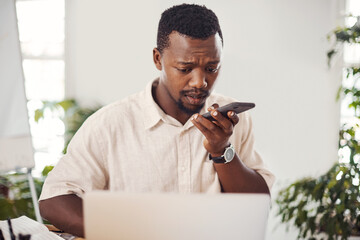 Poster - Please give me call once you get this message. Shot of a young businessman talking on a cellphone while using a laptop in an office.