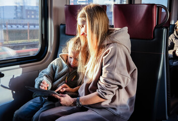 Wall Mural - Mom helps her daughter draw a picture while they are on the train