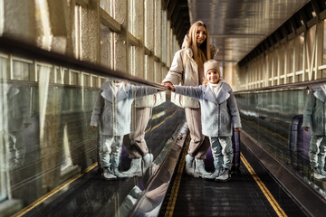 Wall Mural - Mom and daughter go up the escalator to the building of the station