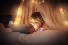 Giving Mom A Break From Bedtime Stories. A Young Girl Lying On Her Bed While Using A Digital Tablet.