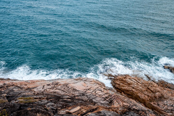 Wall Mural - wild place, stone shore, top view, turquoise sea waves at sunset