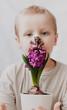 © Margarita - A child with flowers. the child takes care of the flowers. Flowers for Mom. Purple flowers. Geocints. Friendship with nature. A blond boy. A boy with a smile. The hands of a child.