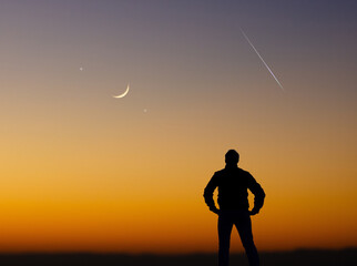 Wall Mural - man observing evening sky with stars, planets, falling stars and crescent moon.
