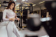 © Jelena Stanojkovic - Fit woman at the gym measuring her waist. Slim young woman measuring her waist with a tape measure. Athlete young woman is holding measuring tape and checking her waist girth.