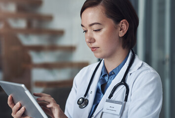 Poster - Please email me when you get the chance. Shot of a young female doctor taking a break to use her digital tablet.