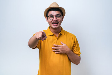 Wall Mural - Young asian man wearing casual shirt laughing at you, pointing finger to the camera