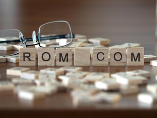 Wall Mural - rom com word or concept represented by wooden letter tiles on a wooden table with glasses and a book