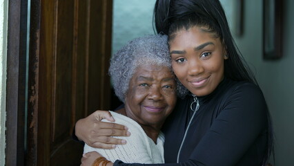 Wall Mural - Grand daughter embracing senior grandmother authentic family love and embrace