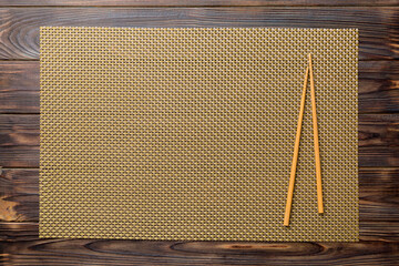 Wall Mural - Two chopsticks and bamboo mat on wooden background. Top view, copy space