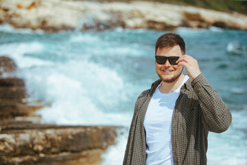 Wall Mural - young man in sunglasses with beard portrait at seaside