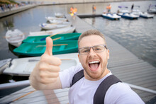 Happy Male Traveler Makes Selfie Photo On Background Of Catamarans Parking. Concept Travel Walk On Sea And Lake
