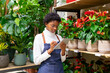 © ADDICTIVE STOCK - Black florist writing on tablet in floral shop