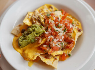 Un plato de nachos con queso, carne y guacamole