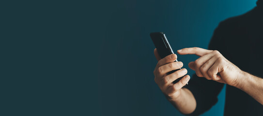 Using a smartphone by a young man on a blank background. Phone in hand while using the Internet, messenger, shopping, communication. Technology, applications, business concept.