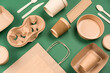 Eco-friendly tableware - kraft paper utensils on green background. Paper cups and containers, wooden cutlery. Street food paper packaging, recyclable paperware concept. Mockup, flat lay
