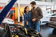 © hedgehog94 - Beautiful young couple choosing a new car at car showroom.
