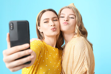 Poster - Portrait of grimacing young sisters taking selfie on color background