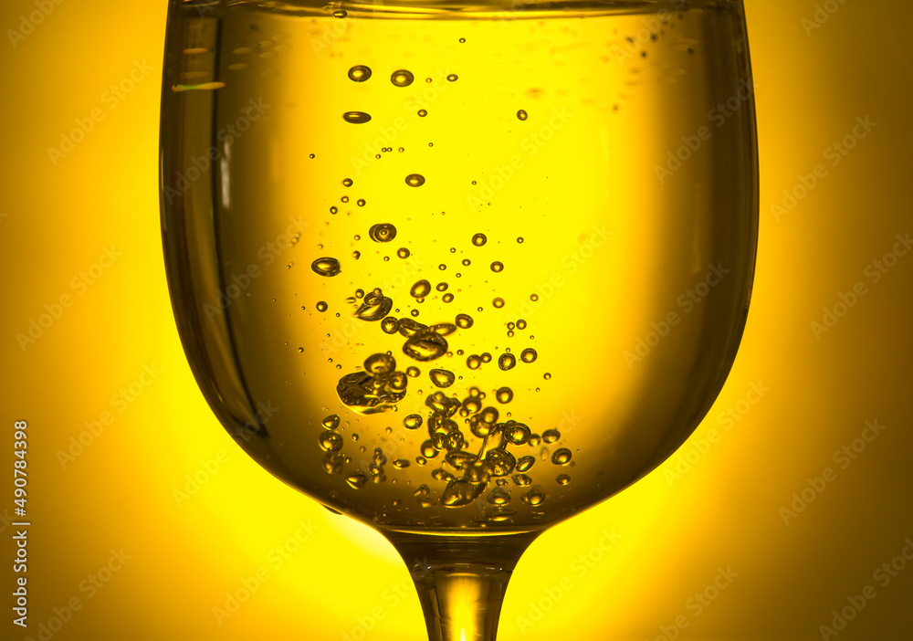 Glass of clear water on yellow background, closeup