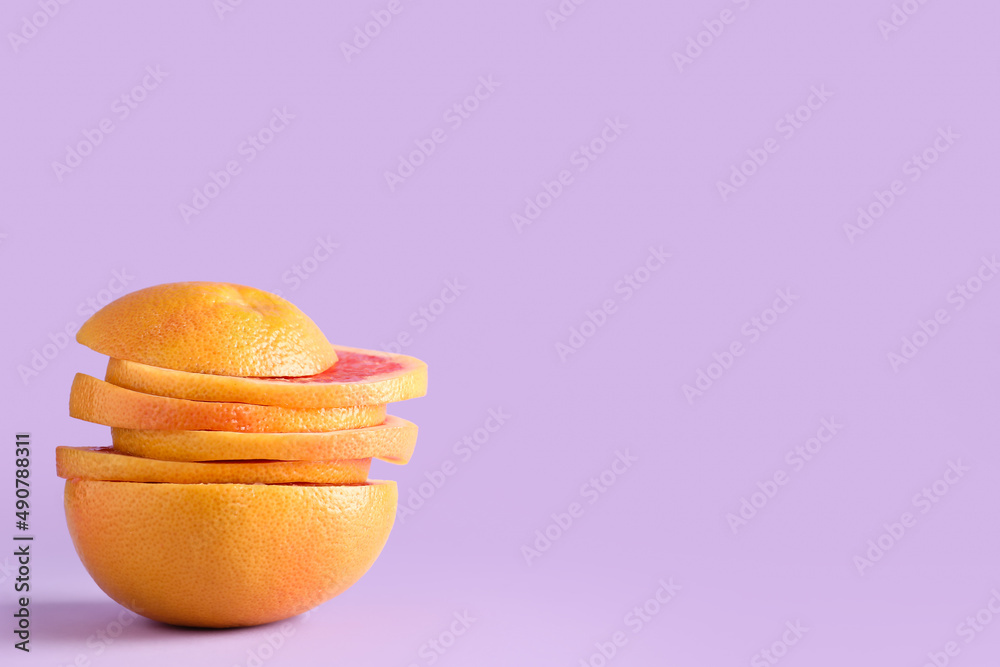 Slices of tasty ripe grapefruit on purple background