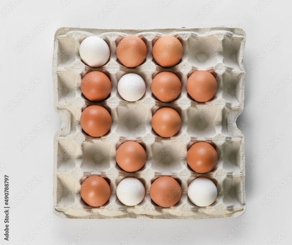 Holder with fresh chicken eggs on light background