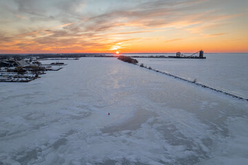 Poster - Aerial view of the frozen sea near the city in winter during sunset