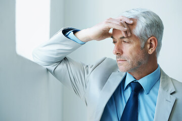 Wall Mural - Time for business. Shot of a stressed-out looking mature businessman leaning against a wall.