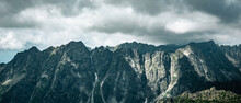 Panoramic View Of A Range Of Rocky Mountains Under A Cloudy Sky