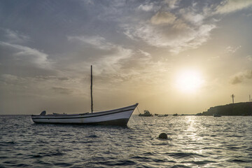 Wall Mural - empty boat moored against the beautiful sunset above the sea.