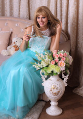 Poster - Vertical shot of a Caucasian woman sitting on a sofa with a vase full of flowers